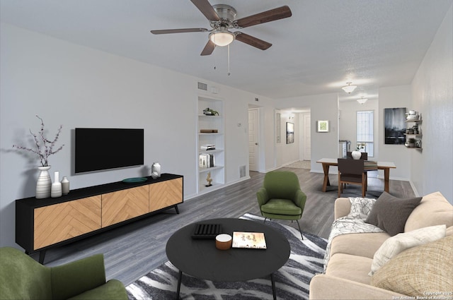 living room with ceiling fan, dark hardwood / wood-style flooring, and built in shelves