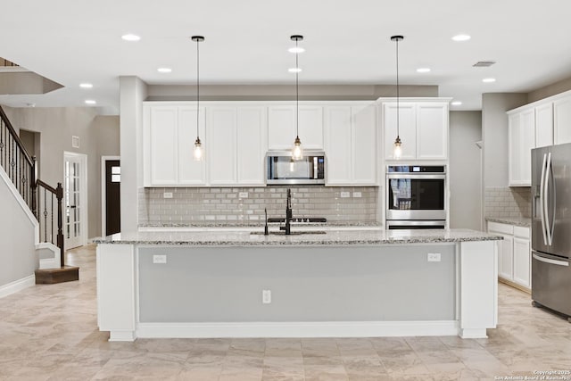 kitchen with stainless steel appliances, an island with sink, and hanging light fixtures