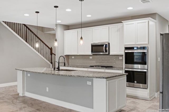 kitchen featuring sink, hanging light fixtures, stainless steel appliances, and an island with sink