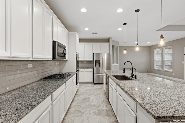 kitchen with sink, appliances with stainless steel finishes, white cabinetry, hanging light fixtures, and a center island with sink