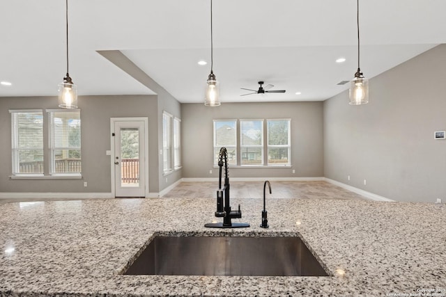 kitchen featuring light stone countertops, sink, a wealth of natural light, and decorative light fixtures