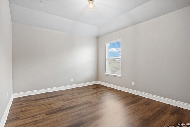 spare room featuring vaulted ceiling and dark hardwood / wood-style floors