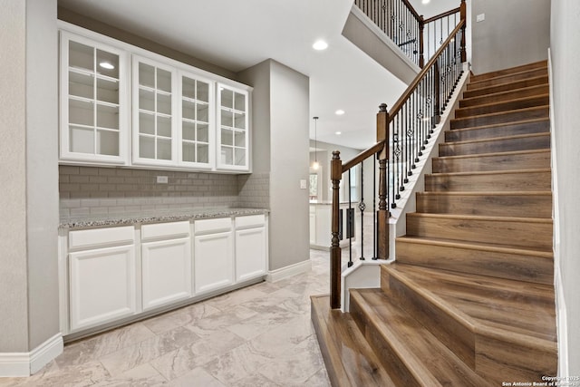 bar featuring tasteful backsplash, light stone countertops, and white cabinets