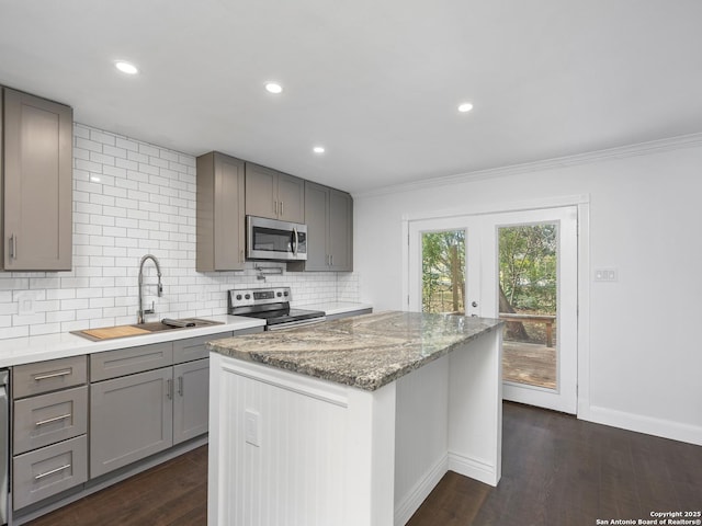 kitchen with sink, stainless steel appliances, tasteful backsplash, light stone countertops, and dark hardwood / wood-style flooring