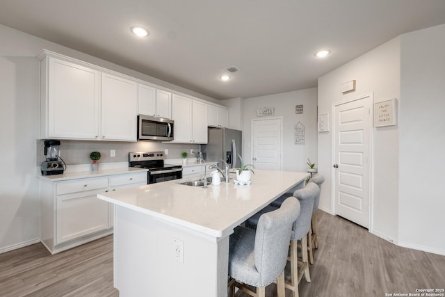 kitchen with stainless steel appliances, sink, a center island with sink, and white cabinets