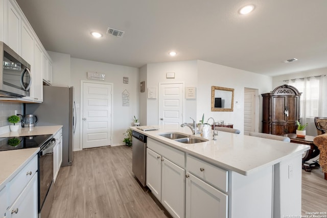 kitchen with white cabinetry, stainless steel appliances, a kitchen island with sink, and sink