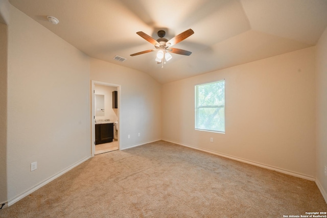 unfurnished bedroom with vaulted ceiling, light colored carpet, ceiling fan, and ensuite bath