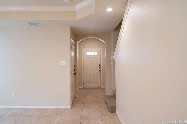 doorway featuring ornamental molding, a raised ceiling, and light tile patterned flooring