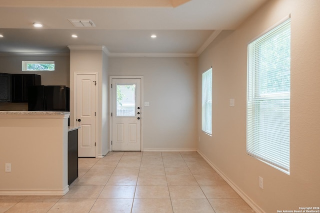 interior space with ornamental molding, black refrigerator, and light tile patterned floors