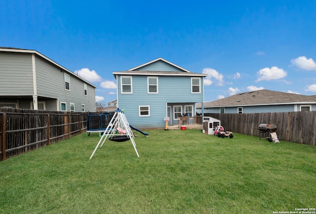 back of property featuring a trampoline and a lawn