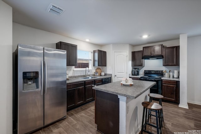 kitchen featuring sink, stainless steel fridge, a center island, a kitchen bar, and black / electric stove