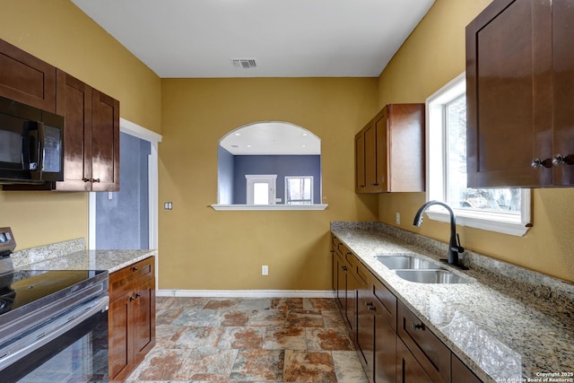 kitchen featuring light stone counters, sink, electric range, and a healthy amount of sunlight