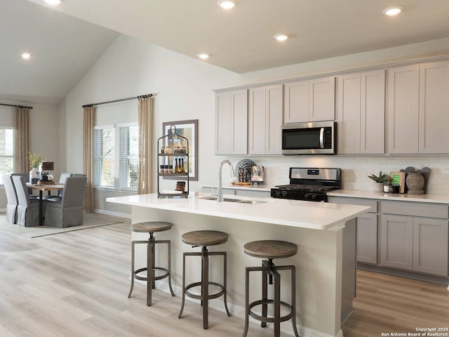 kitchen with stainless steel appliances, sink, a kitchen island with sink, and gray cabinets