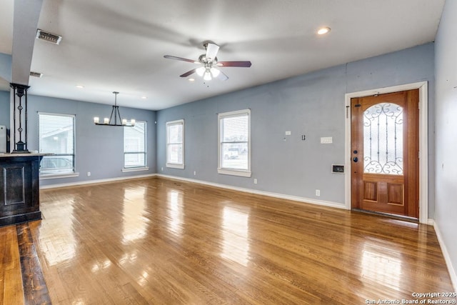 unfurnished living room featuring hardwood / wood-style flooring and ceiling fan with notable chandelier