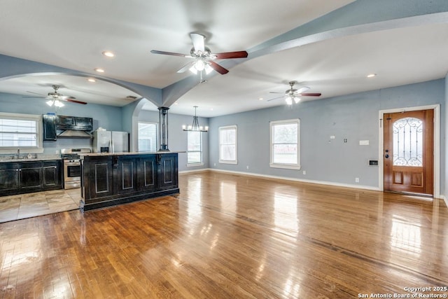 kitchen with decorative light fixtures, a center island, appliances with stainless steel finishes, light hardwood / wood-style floors, and ceiling fan with notable chandelier