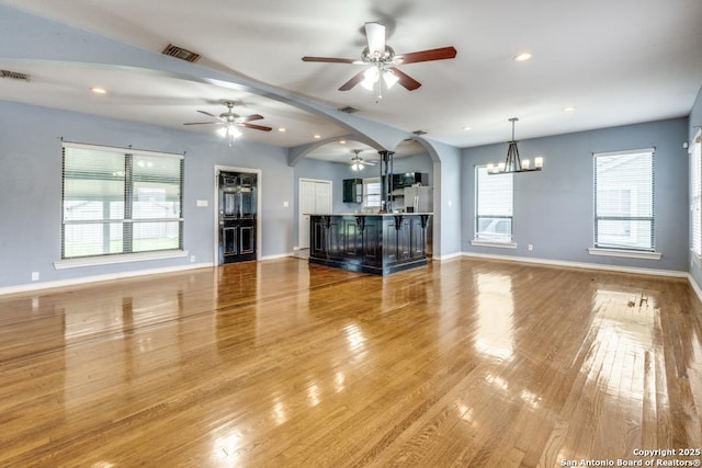 unfurnished living room featuring ceiling fan with notable chandelier and light hardwood / wood-style floors