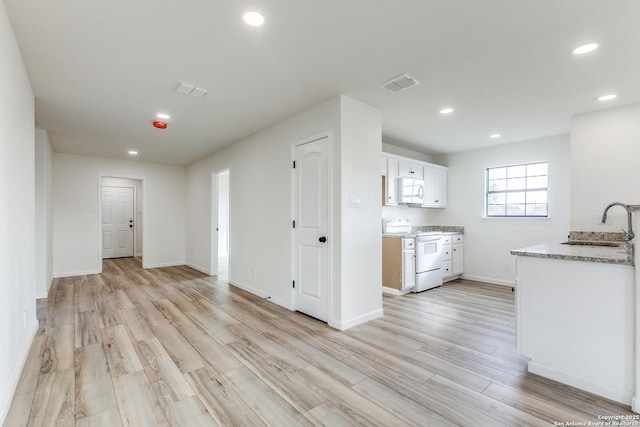 kitchen with white cabinetry, white appliances, sink, and light hardwood / wood-style flooring