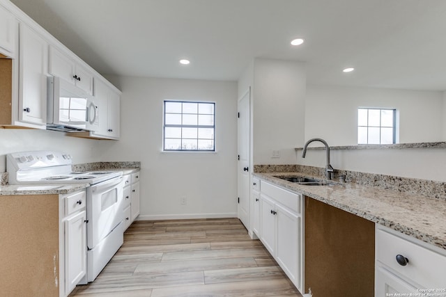 kitchen with sink, light stone counters, a wealth of natural light, white appliances, and white cabinets