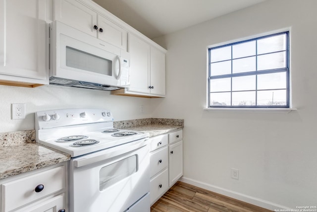 kitchen featuring white appliances, light stone countertops, light wood-type flooring, and white cabinets