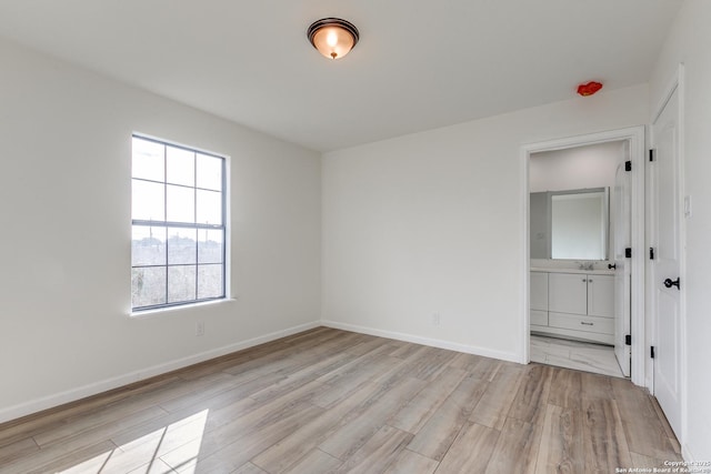 unfurnished bedroom with ensuite bath, sink, and light hardwood / wood-style floors