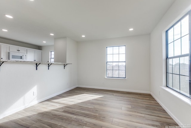 empty room with light hardwood / wood-style floors and a healthy amount of sunlight