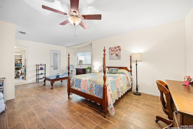 bedroom featuring ceiling fan, wood-type flooring, and a textured ceiling