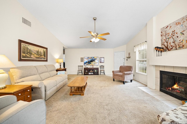 living room featuring a tile fireplace, lofted ceiling, light colored carpet, and ceiling fan