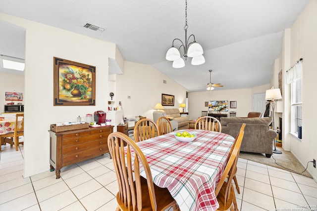 dining space with lofted ceiling, light tile patterned floors, ceiling fan with notable chandelier, and a textured ceiling