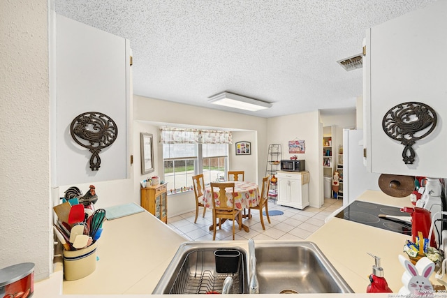 kitchen featuring white cabinetry, sink, a textured ceiling, and light tile patterned flooring