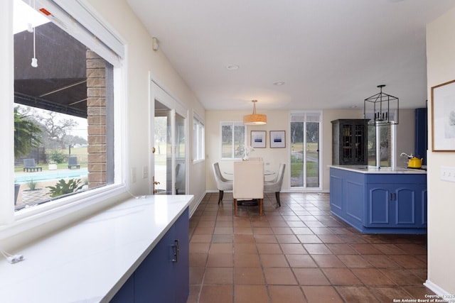 kitchen featuring decorative light fixtures, blue cabinetry, and dark tile patterned floors