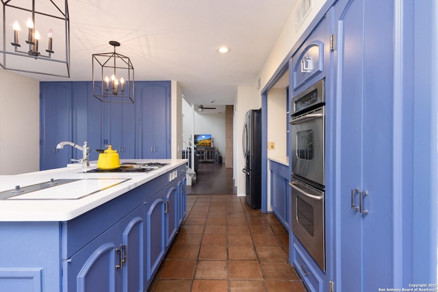 kitchen with hanging light fixtures, blue cabinetry, and appliances with stainless steel finishes