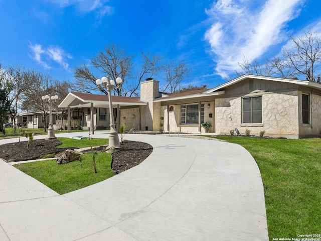 ranch-style house featuring a front yard, curved driveway, and a chimney