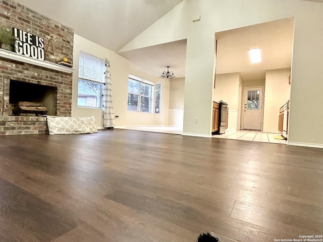 living room with high vaulted ceiling, a fireplace, and light hardwood / wood-style floors