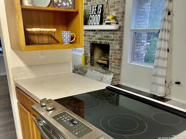 kitchen featuring stainless steel range with electric stovetop, hardwood / wood-style floors, and a brick fireplace