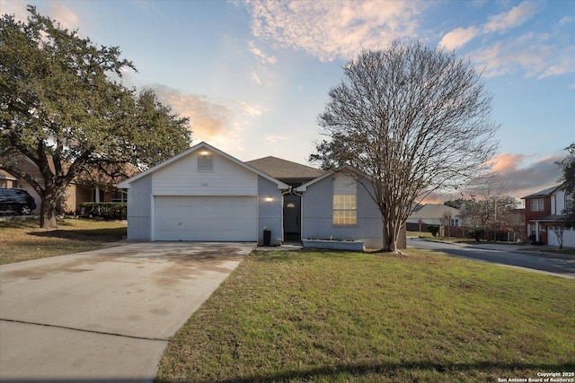 ranch-style house featuring a garage and a yard