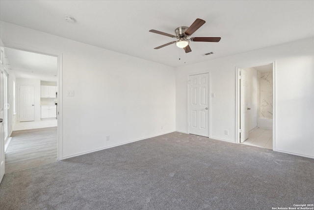 unfurnished bedroom featuring light carpet, ceiling fan, and ensuite bath