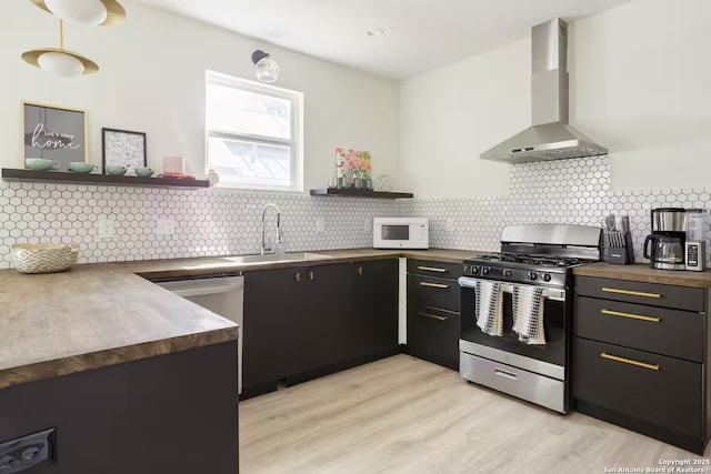 kitchen featuring wall chimney range hood, stainless steel appliances, tasteful backsplash, and sink