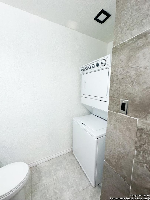 clothes washing area featuring light tile patterned flooring and stacked washer and dryer