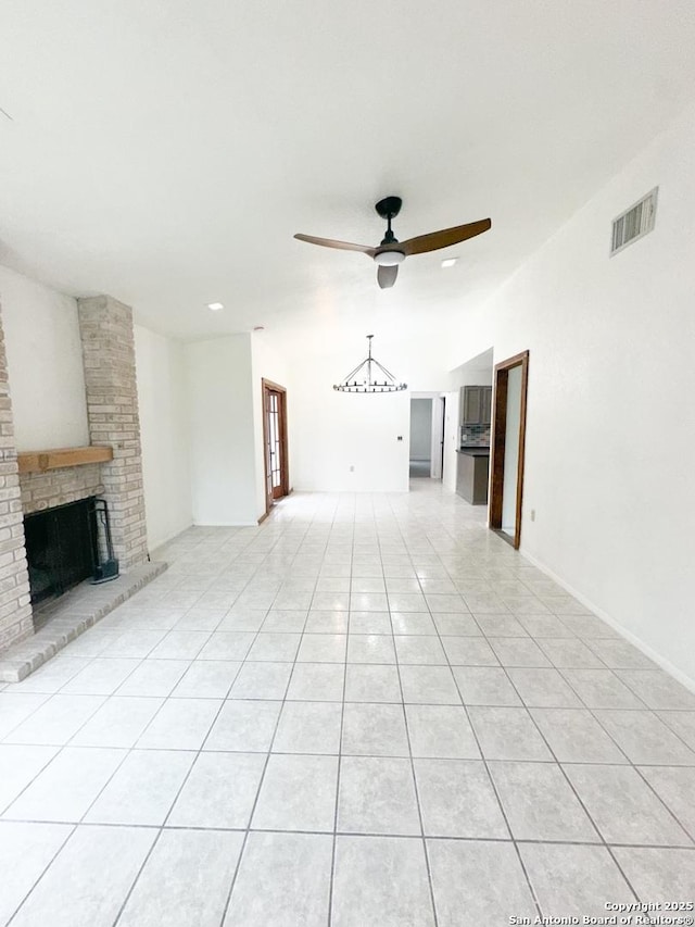 unfurnished living room featuring light tile patterned flooring, ceiling fan, a fireplace, and vaulted ceiling