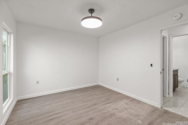 spare room with light hardwood / wood-style flooring and a textured ceiling