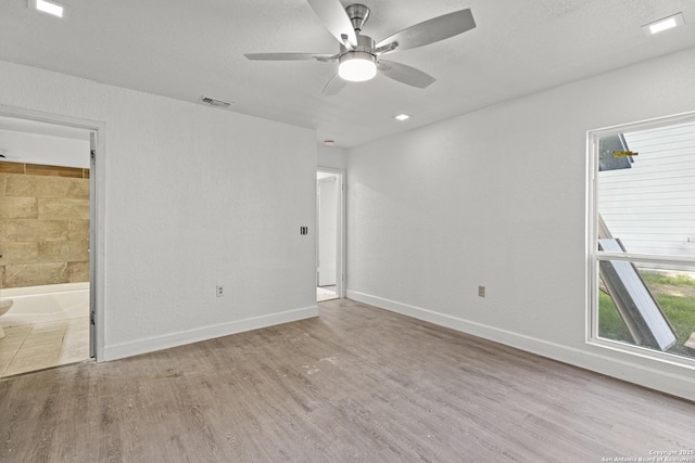 spare room with ceiling fan, light hardwood / wood-style flooring, and a textured ceiling