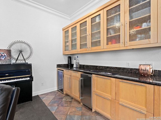 kitchen featuring dark stone countertops, light brown cabinetry, ornamental molding, and beverage cooler