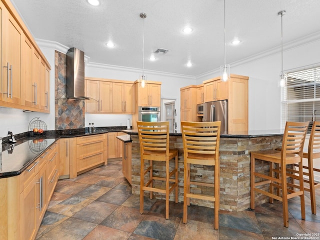 kitchen with appliances with stainless steel finishes, hanging light fixtures, ventilation hood, a kitchen bar, and light brown cabinetry