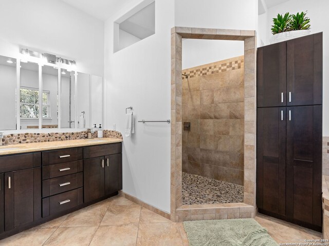 bathroom with tiled shower, vanity, and decorative backsplash