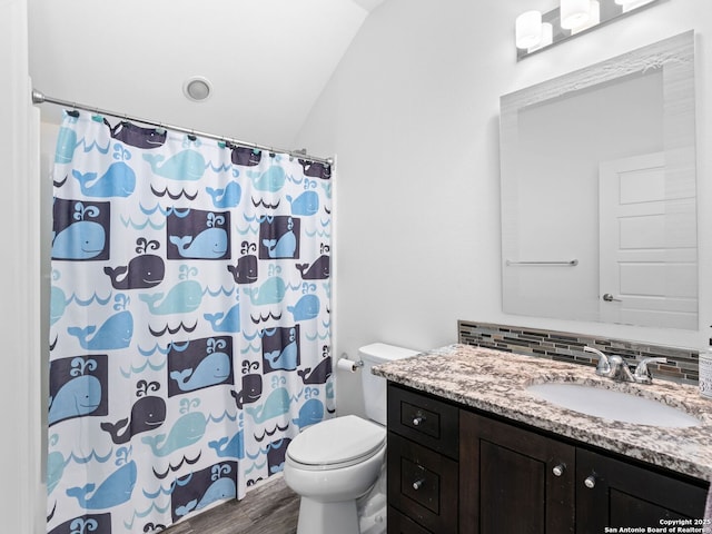 bathroom with toilet, tasteful backsplash, vaulted ceiling, vanity, and hardwood / wood-style flooring