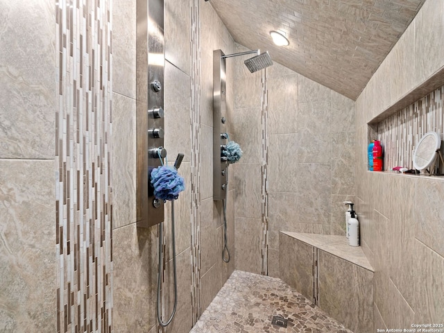 bathroom with a tile shower and lofted ceiling