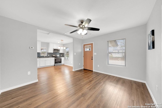 unfurnished living room with sink, hardwood / wood-style flooring, and ceiling fan