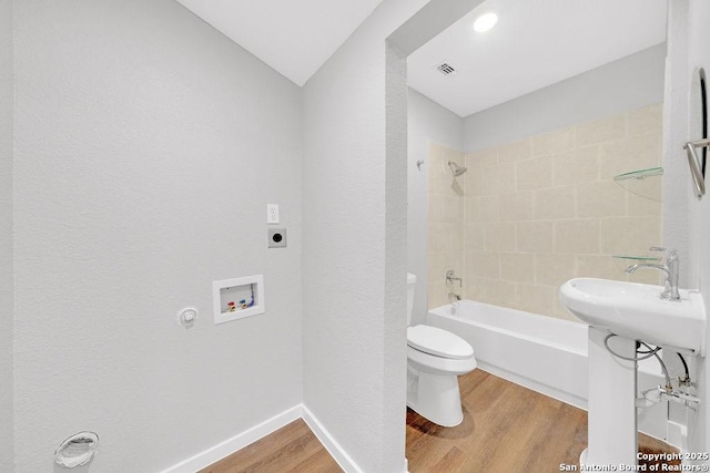 full bathroom featuring sink, wood-type flooring, toilet, and tiled shower / bath