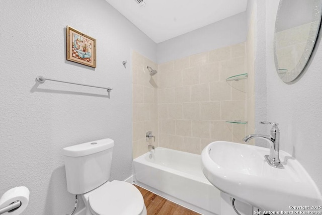 full bathroom with tiled shower / bath combo, wood-type flooring, sink, and toilet