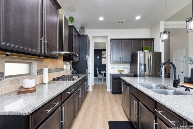 kitchen with sink, hanging light fixtures, stainless steel appliances, light stone countertops, and backsplash